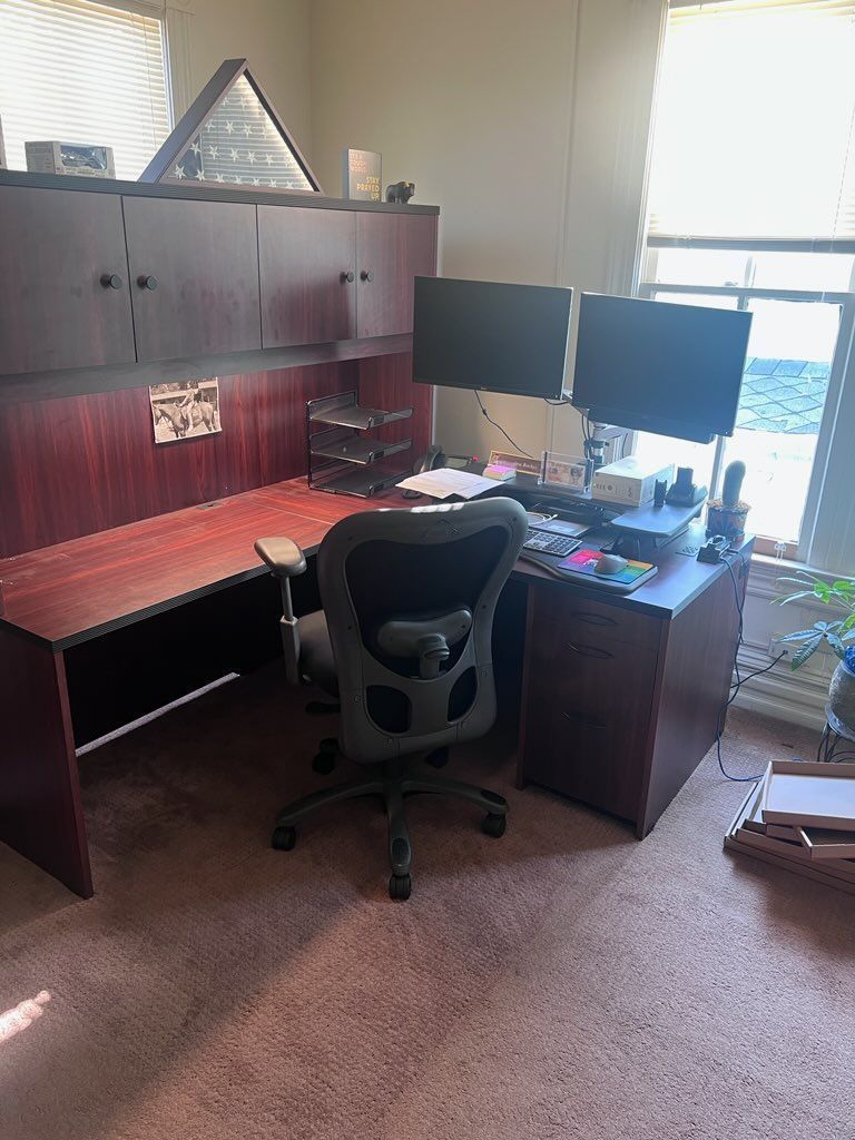 A desk with two monitors and a chair in a room.
