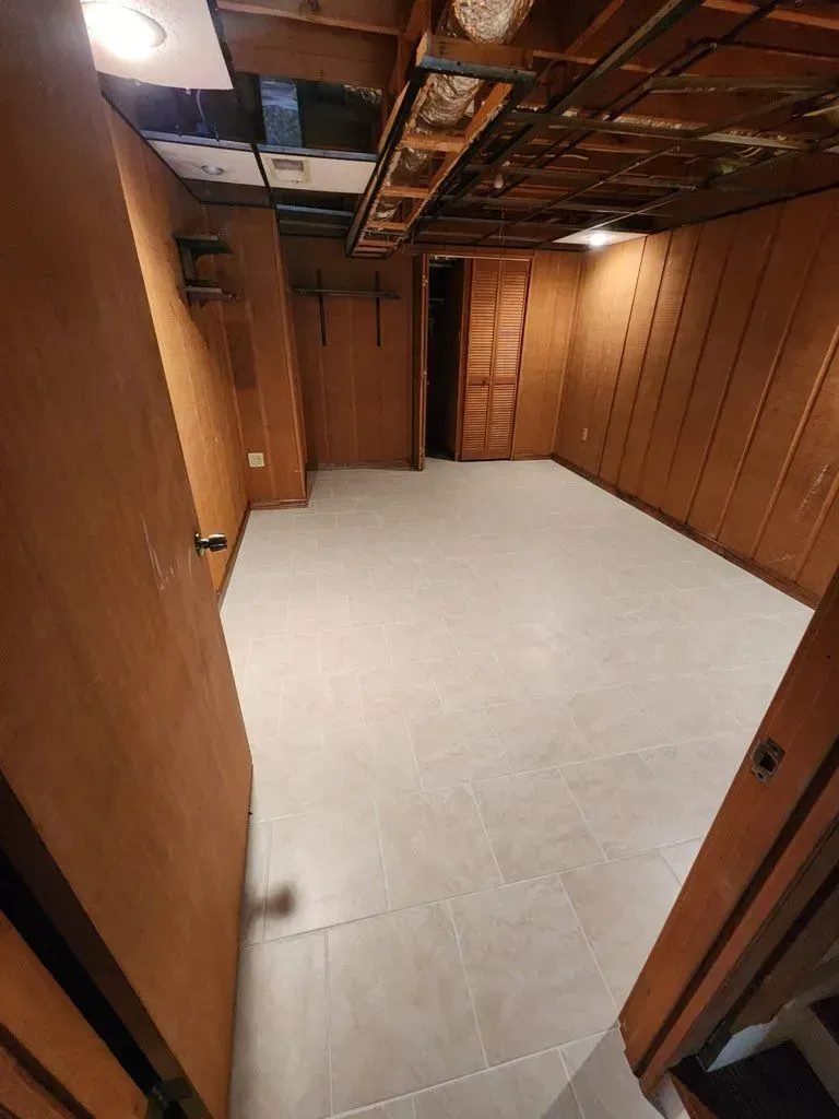 An empty basement with a tiled floor and wooden walls.