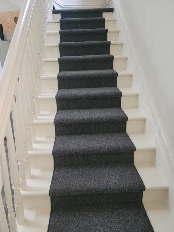 A staircase with a black carpet on the steps