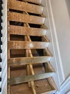 A wooden staircase is being built in a house.