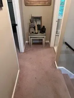 A hallway with a table and stairs in a house.