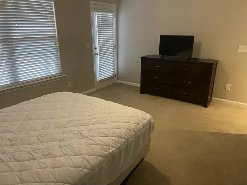 A bedroom with a bed , dresser and television