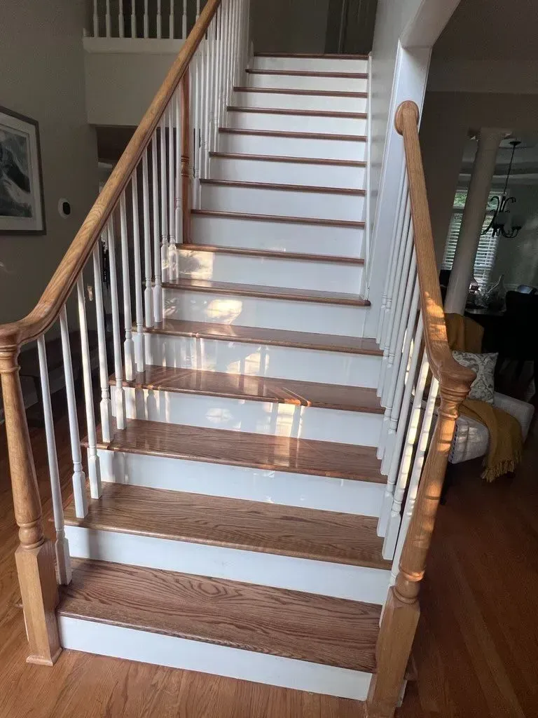 A white staircase with wooden steps and a wooden railing in a living room.