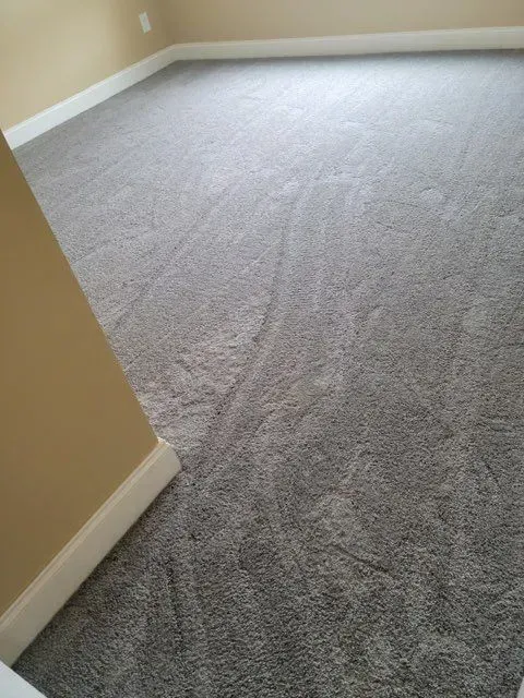A room with a gray carpeted floor and beige walls.