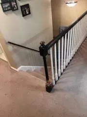 A staircase with a black and white railing and a carpeted floor.