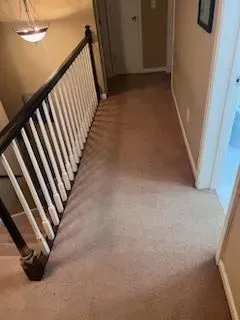 A hallway with stairs and a railing in a house.