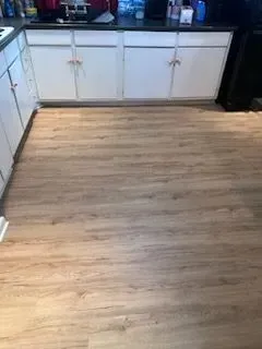 A kitchen with a wooden floor and white cabinets.
