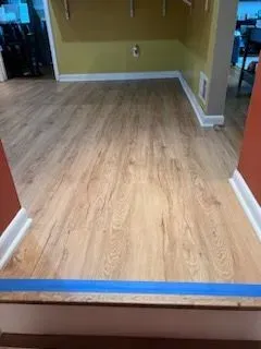A room with a wooden floor and a blue tape on the floor.