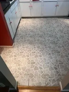 A kitchen with a tile floor and white cabinets.