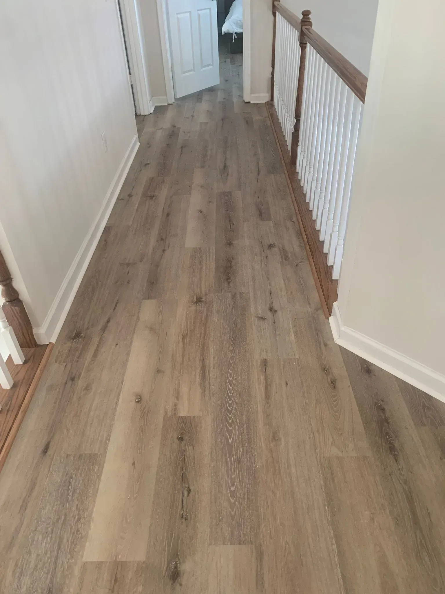 A hallway with hardwood floors and stairs in a house.