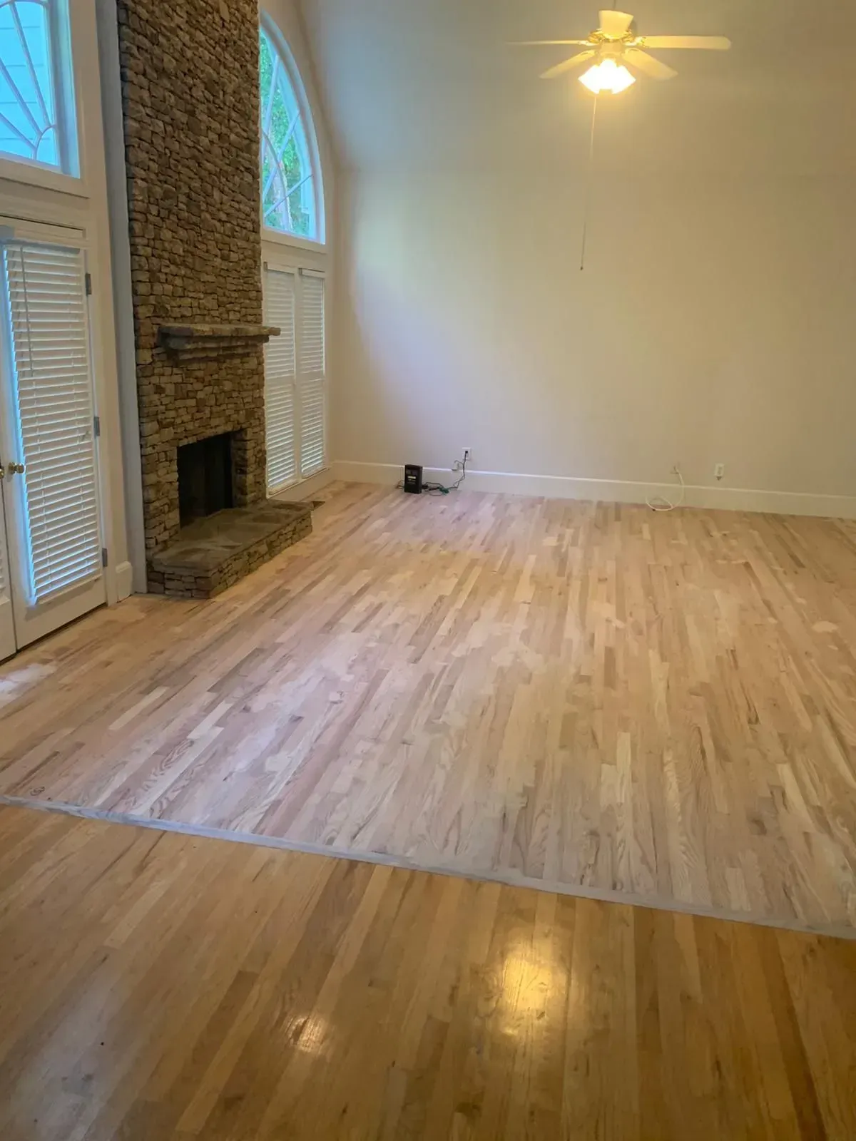 An empty living room with hardwood floors and a fireplace.
