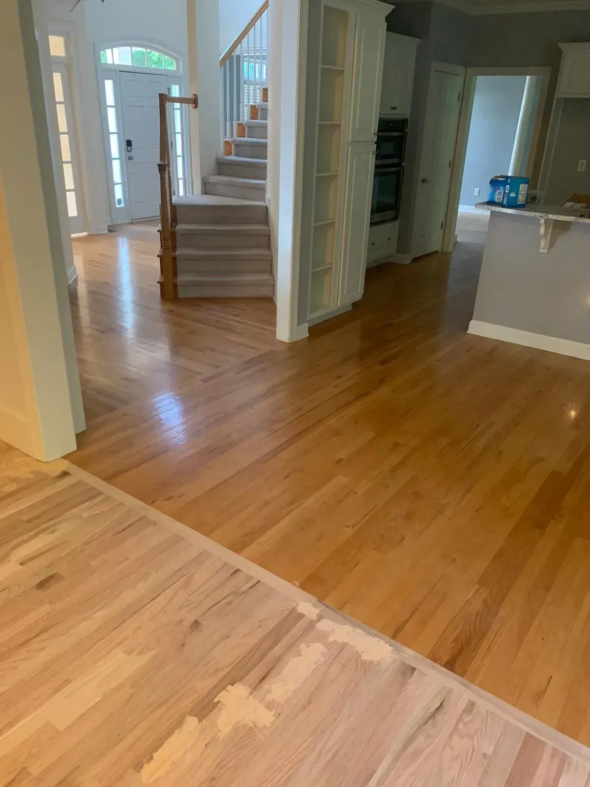A living room with hardwood floors and stairs in a house.