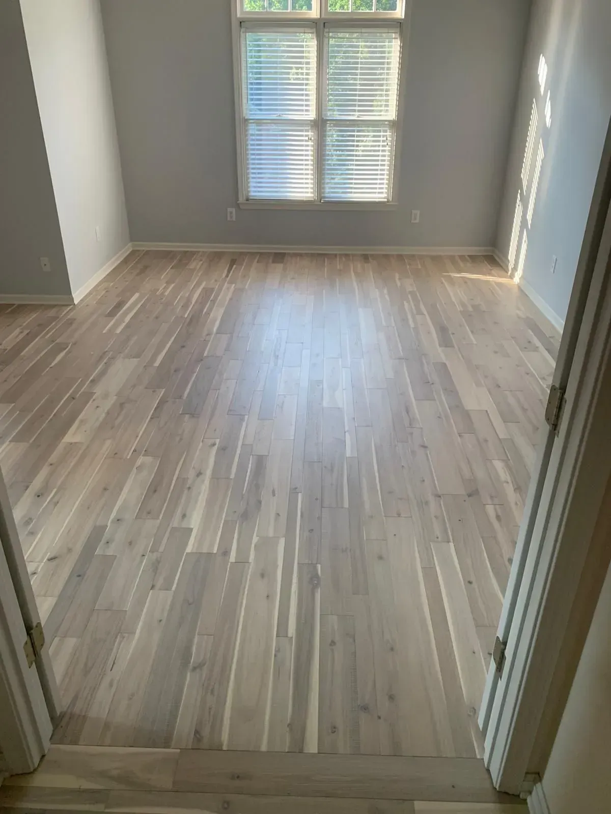 An empty room with hardwood floors and a window.
