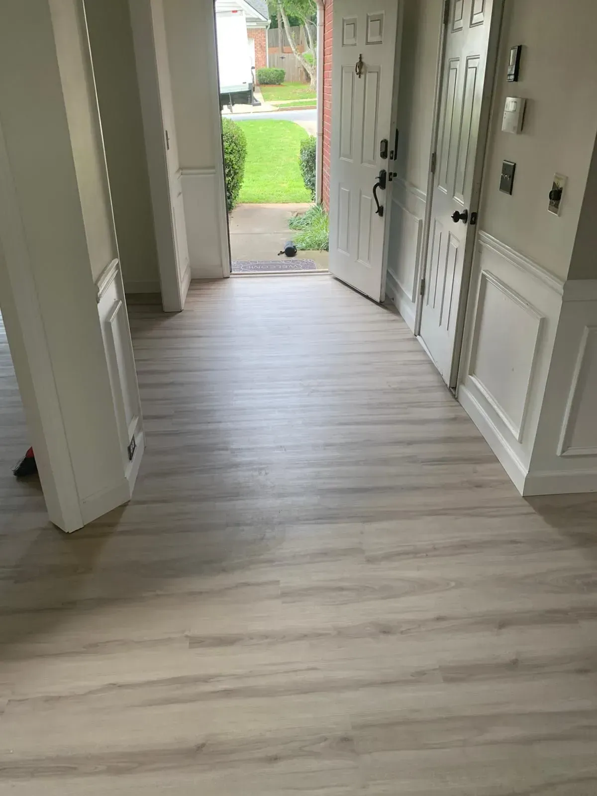 A hallway with a wooden floor and white doors in a house.