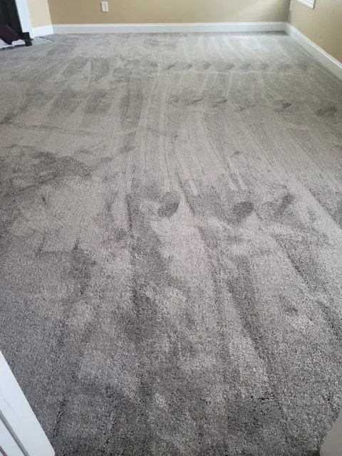 A living room with a gray carpeted floor and beige walls.