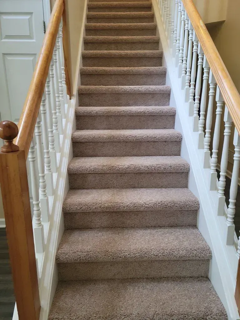 A set of stairs with carpeted steps and a wooden railing.