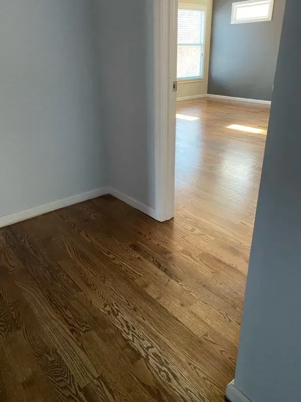 A room with hardwood floors and a doorway leading to a living room.