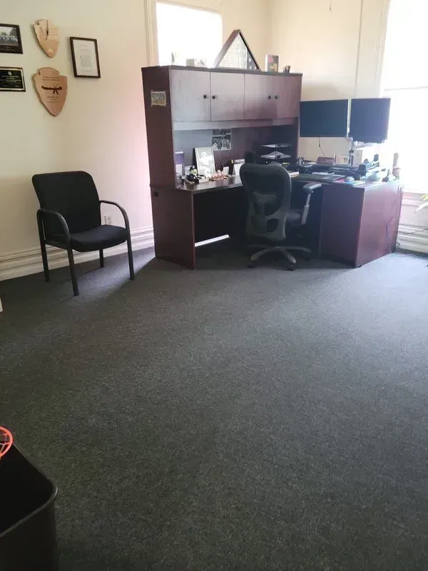 A room with a desk chair and two monitors