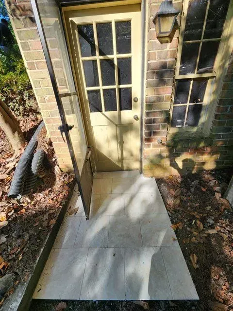 A brick building with a yellow door and a walkway leading to it.