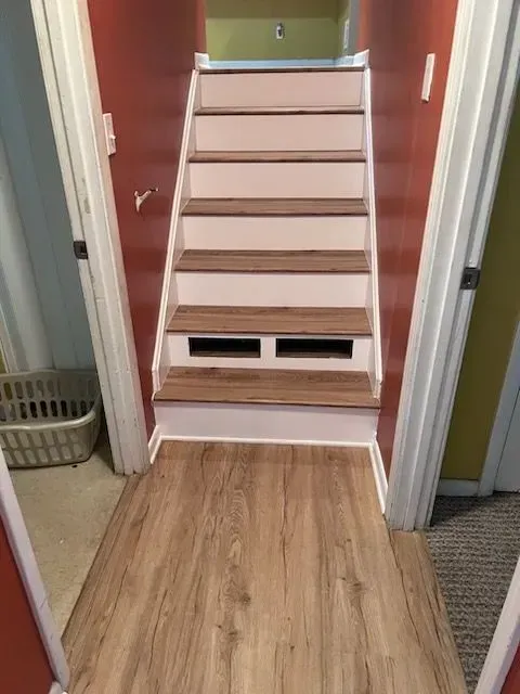 A hallway with wooden floors and stairs in a house.