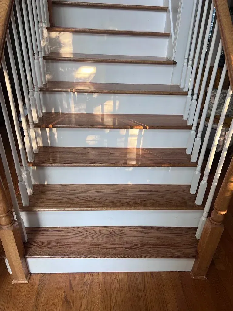 A staircase with wooden steps and white railing in a house.