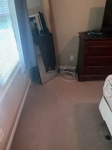 A bedroom with a bed , dresser , mirror and television.