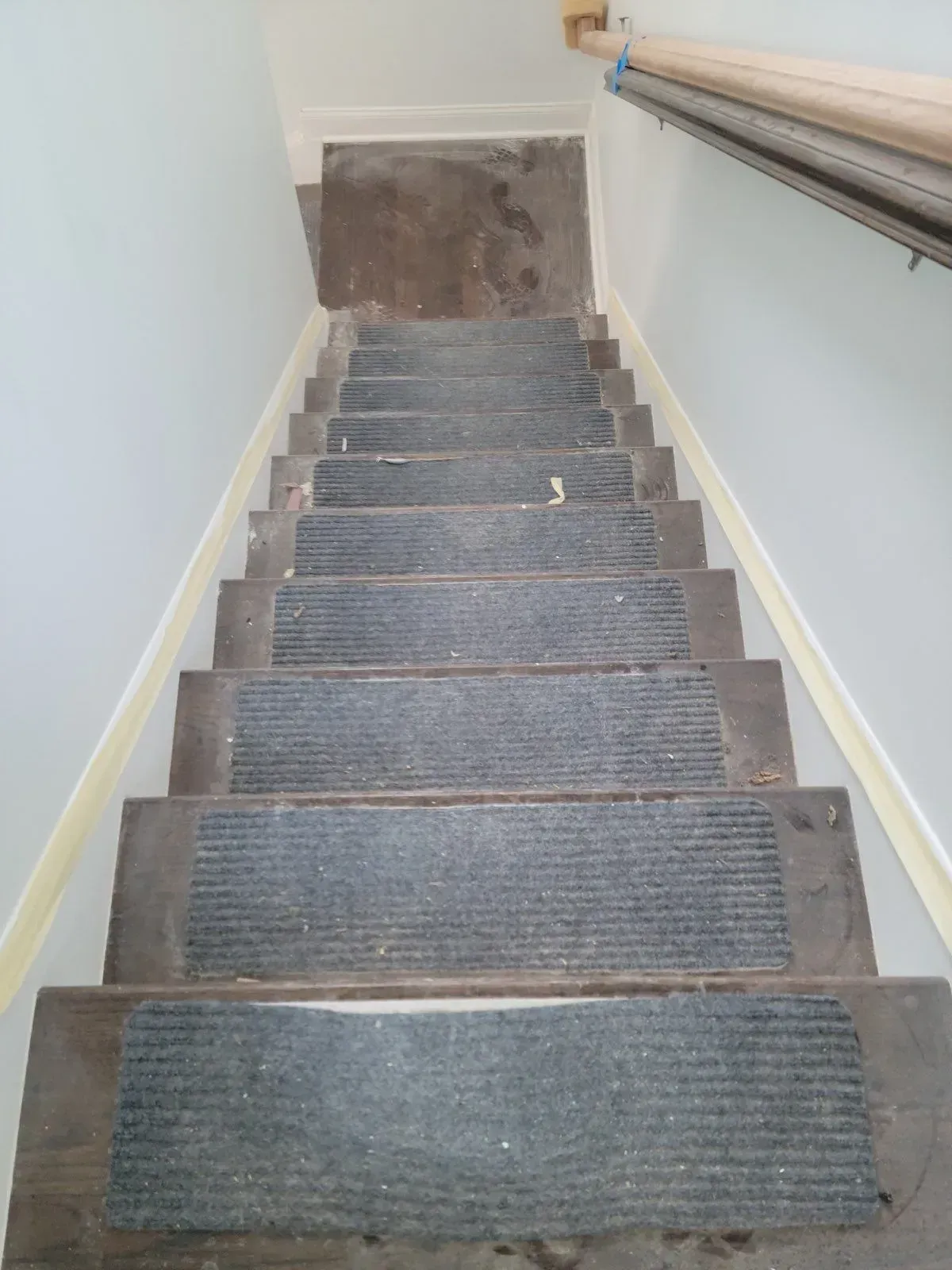 A staircase with a rug on the steps and a railing.