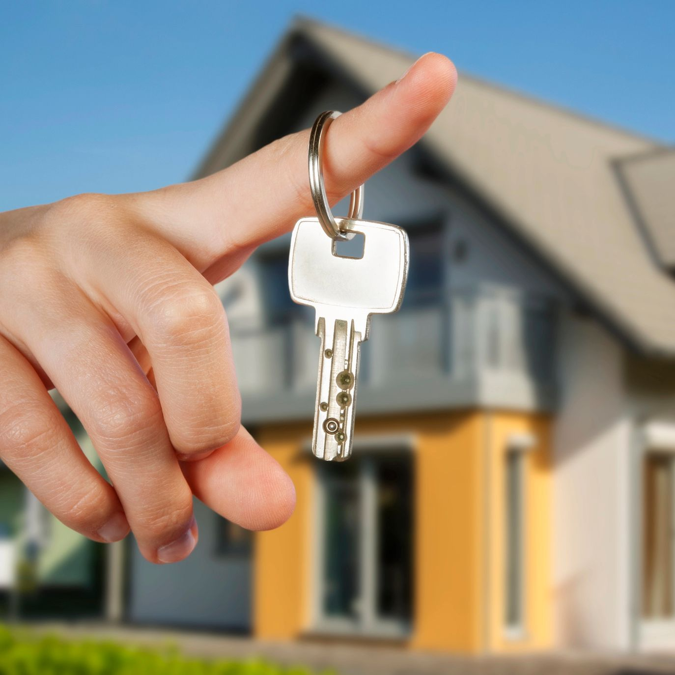 Mano che tiene la chiave di casa con sfondo sfocato.