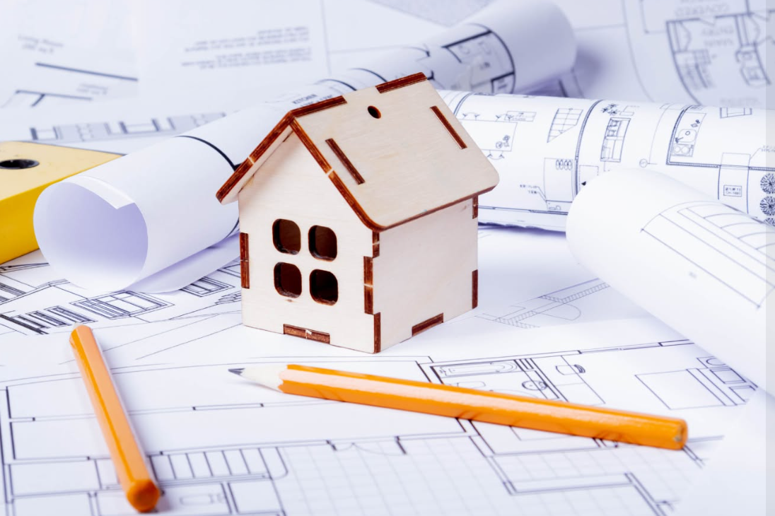 Modello di casa in legno basato su progetti architettonici, con matite e progetti arrotolati.