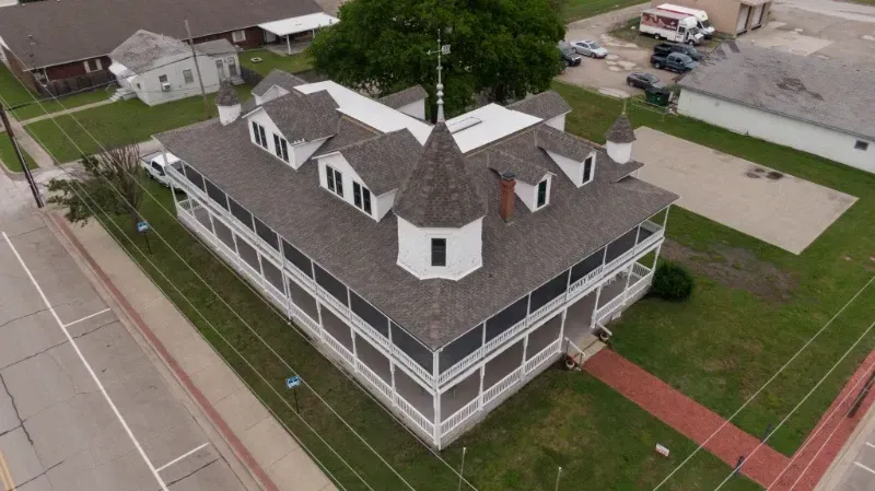 An aerial view of a large white building with a gray roof.