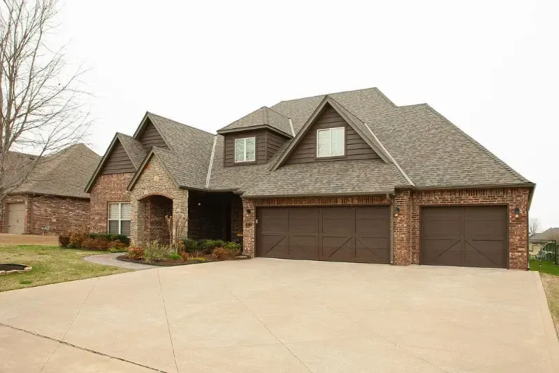 A large brick house with two garage doors and a driveway.