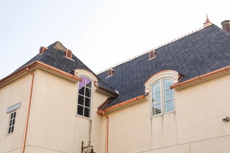 A large white building with a copper gutter and a slate roof.