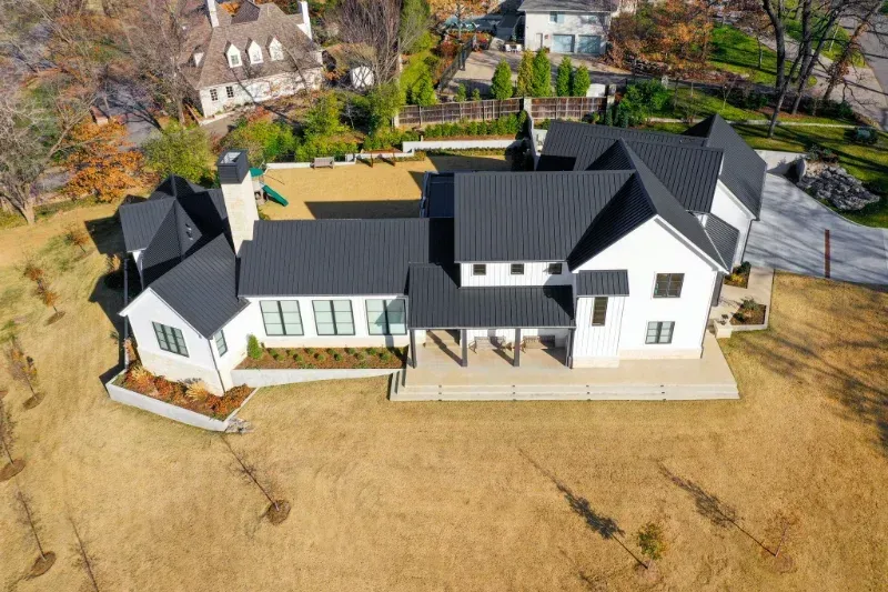 An aerial view of a large white house with a black roof