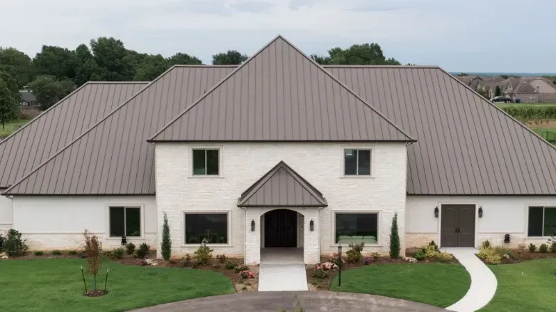 A large white house with a brown roof and a walkway leading to it.
