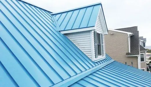 A blue metal roof on a house with a window.