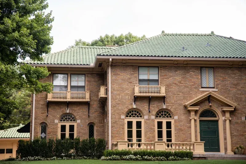 A large brick house with a green tiled roof