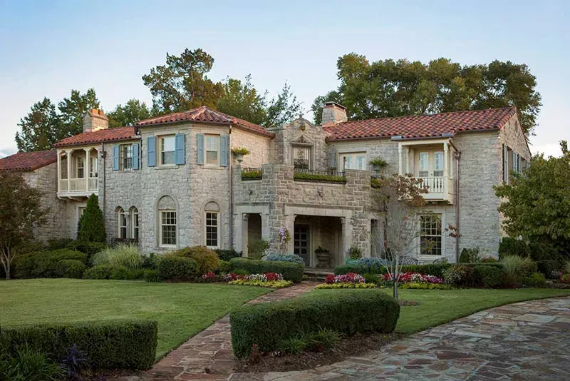 A large stone house with a red tile roof and blue shutters
