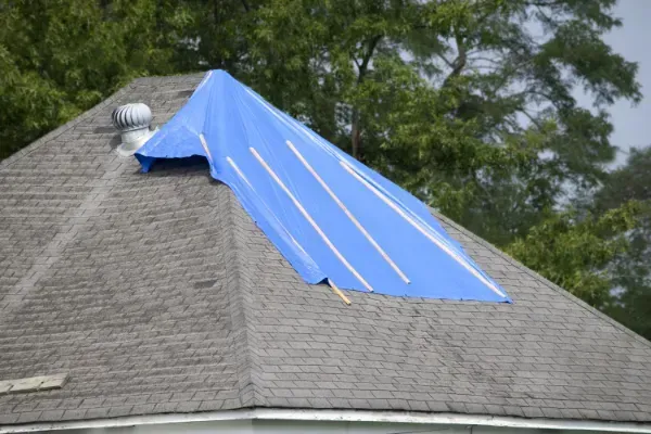 A blue tarp is covering the roof of a house.