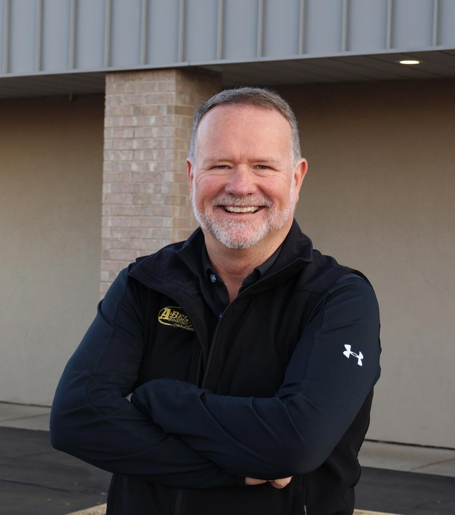 A man with a beard is smiling with his arms crossed