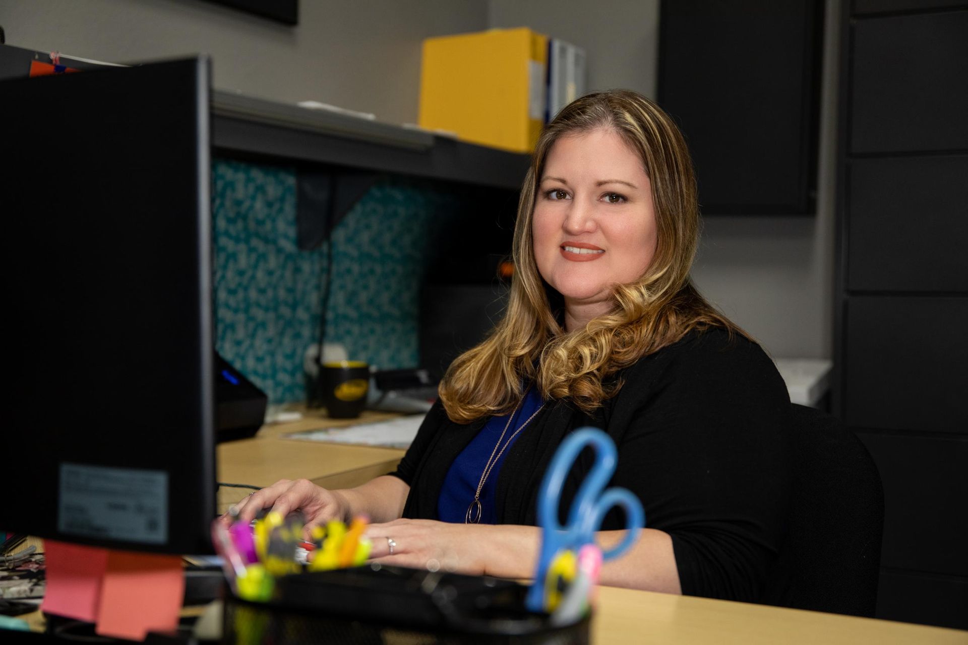A woman is sitting at a desk in front of a computer.