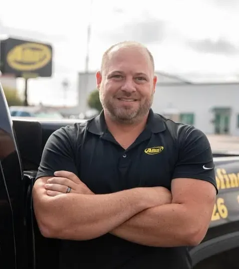 A man with his arms crossed standing next to a truck