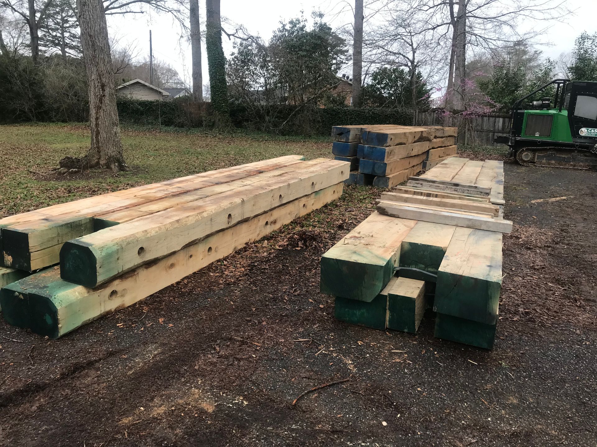 Pile of treated lumber outdoors, some with blue and green end caps.