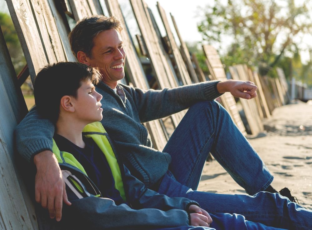 a man and a boy are sitting on the ground talking