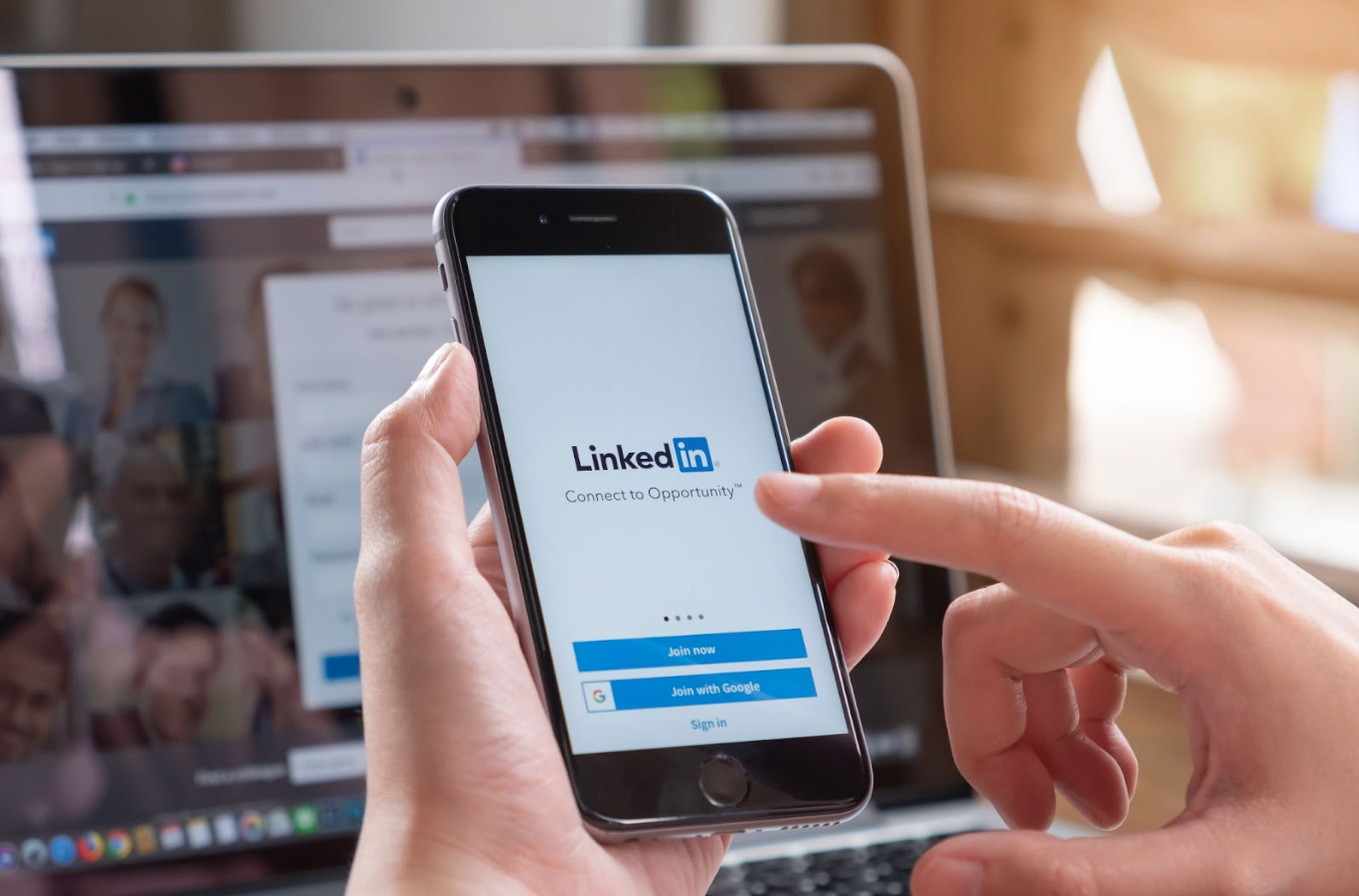 A person is holding a cell phone with the words LinkedIn on it