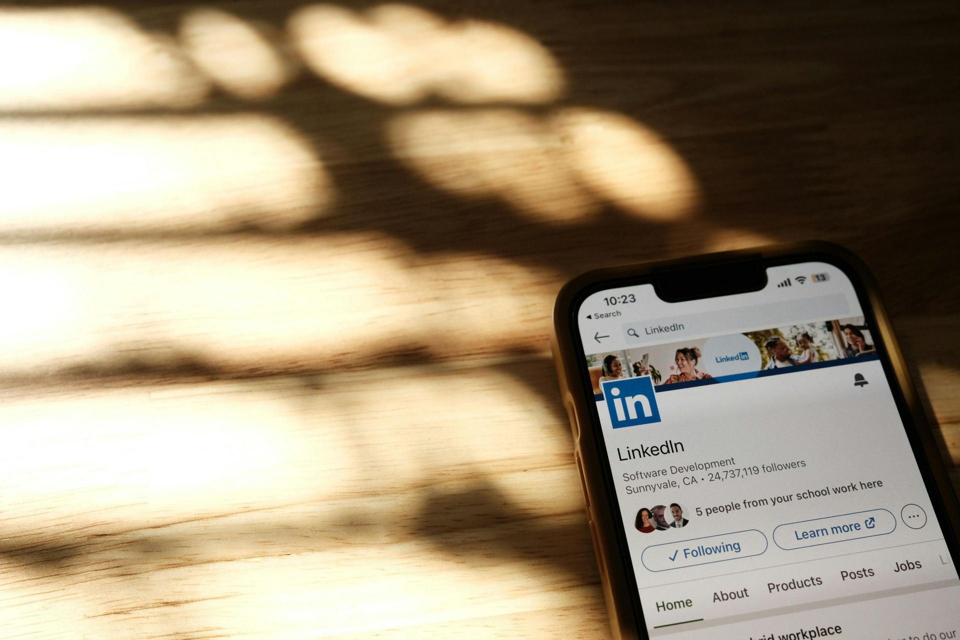A cell phone is sitting on a wooden table with LinkedIn app open
