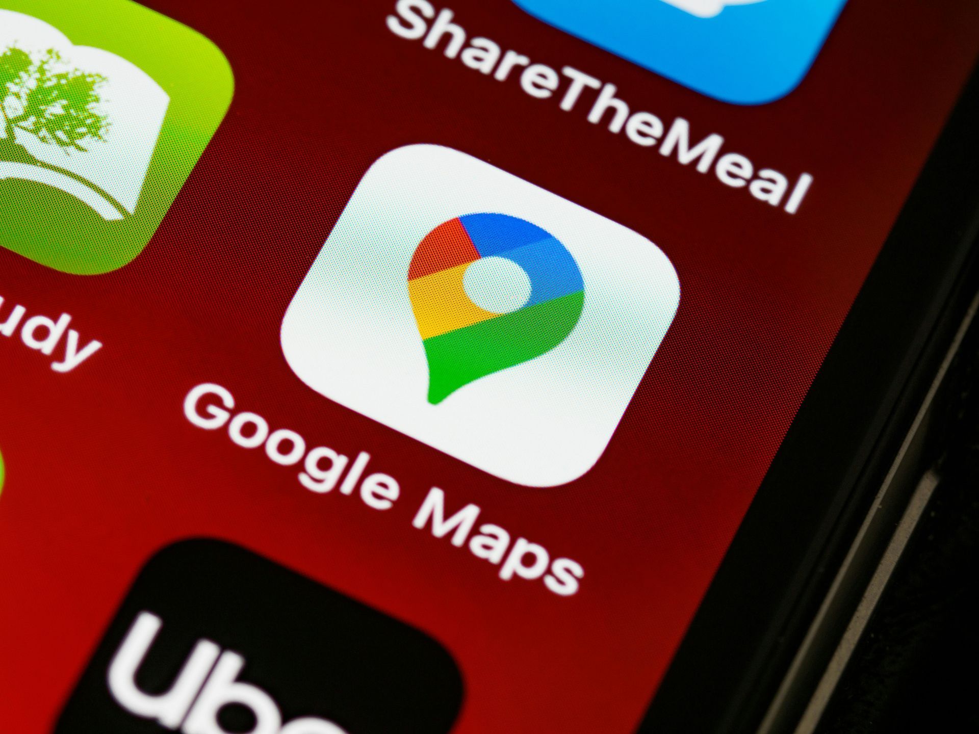 Close-up of a smartphone screen showing the Google Maps app icon and label on a red background.