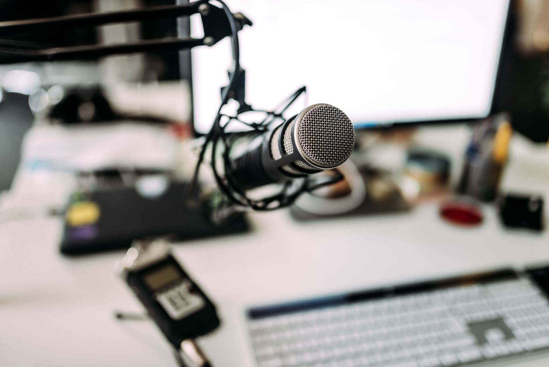 A microphone is sitting on a desk in front of a computer.
