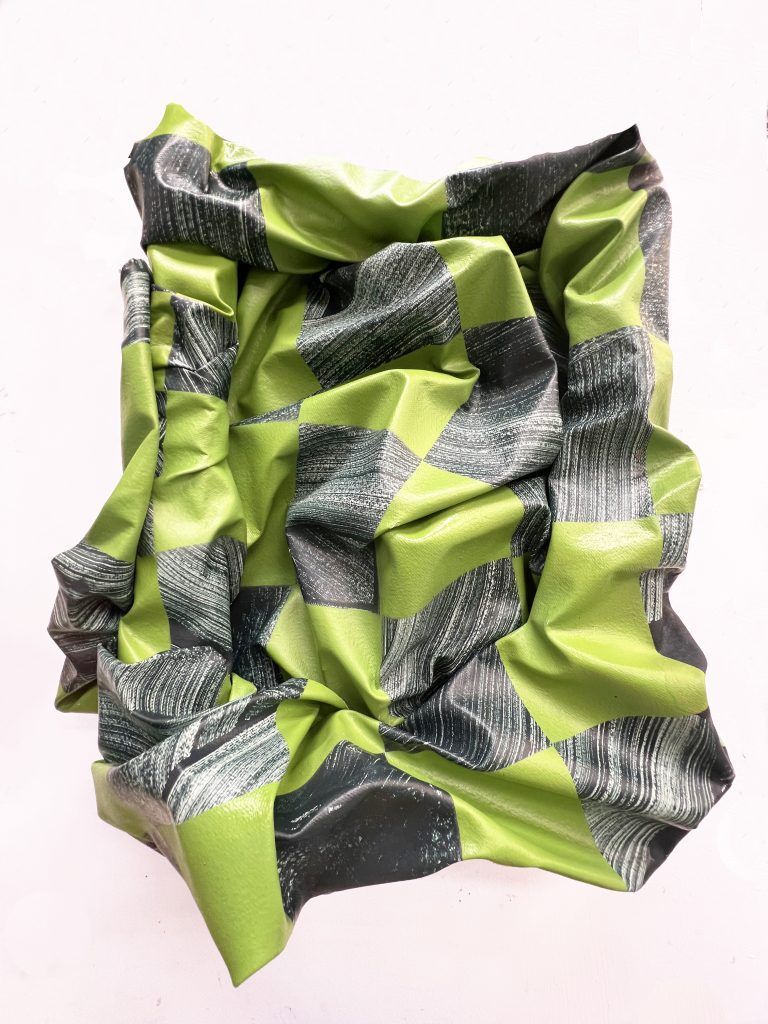 Green and black checkered, crumpled art piece, with a white background.