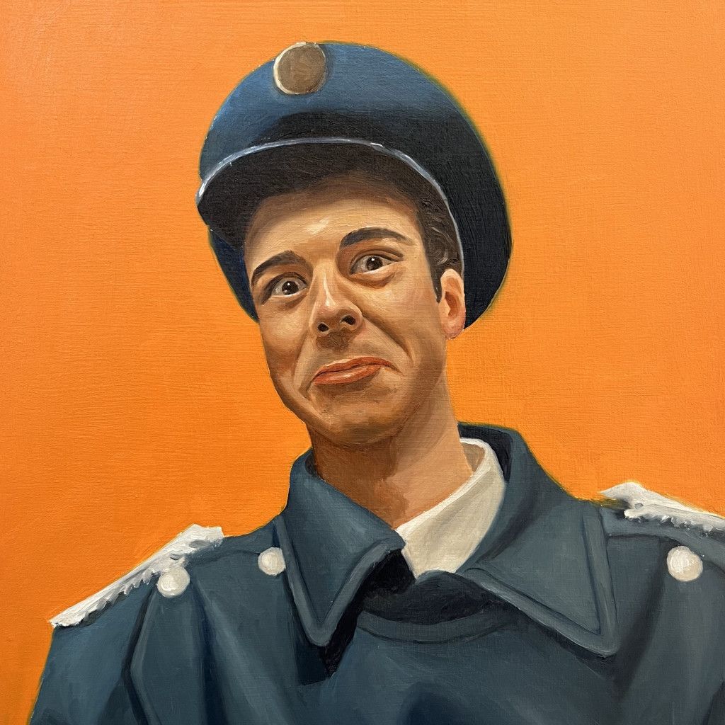 Man in dark blue uniform and hat against an orange background. He smiles with raised eyebrows.