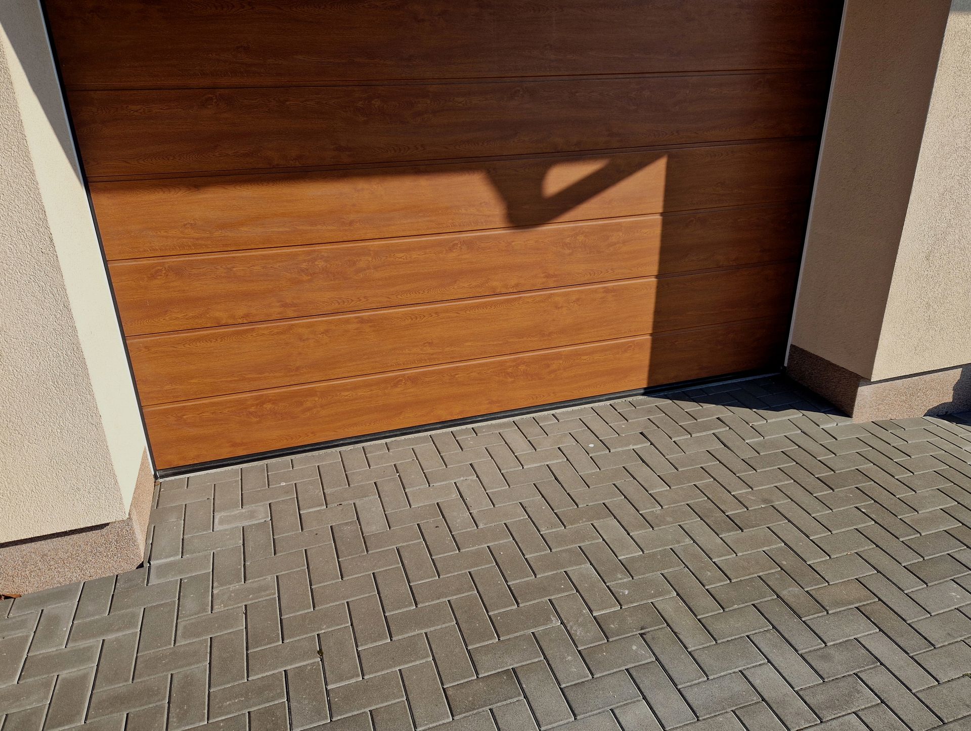Wooden garage door with shadow on brick driveway. Wooden garage door with shadow on brick driveway.